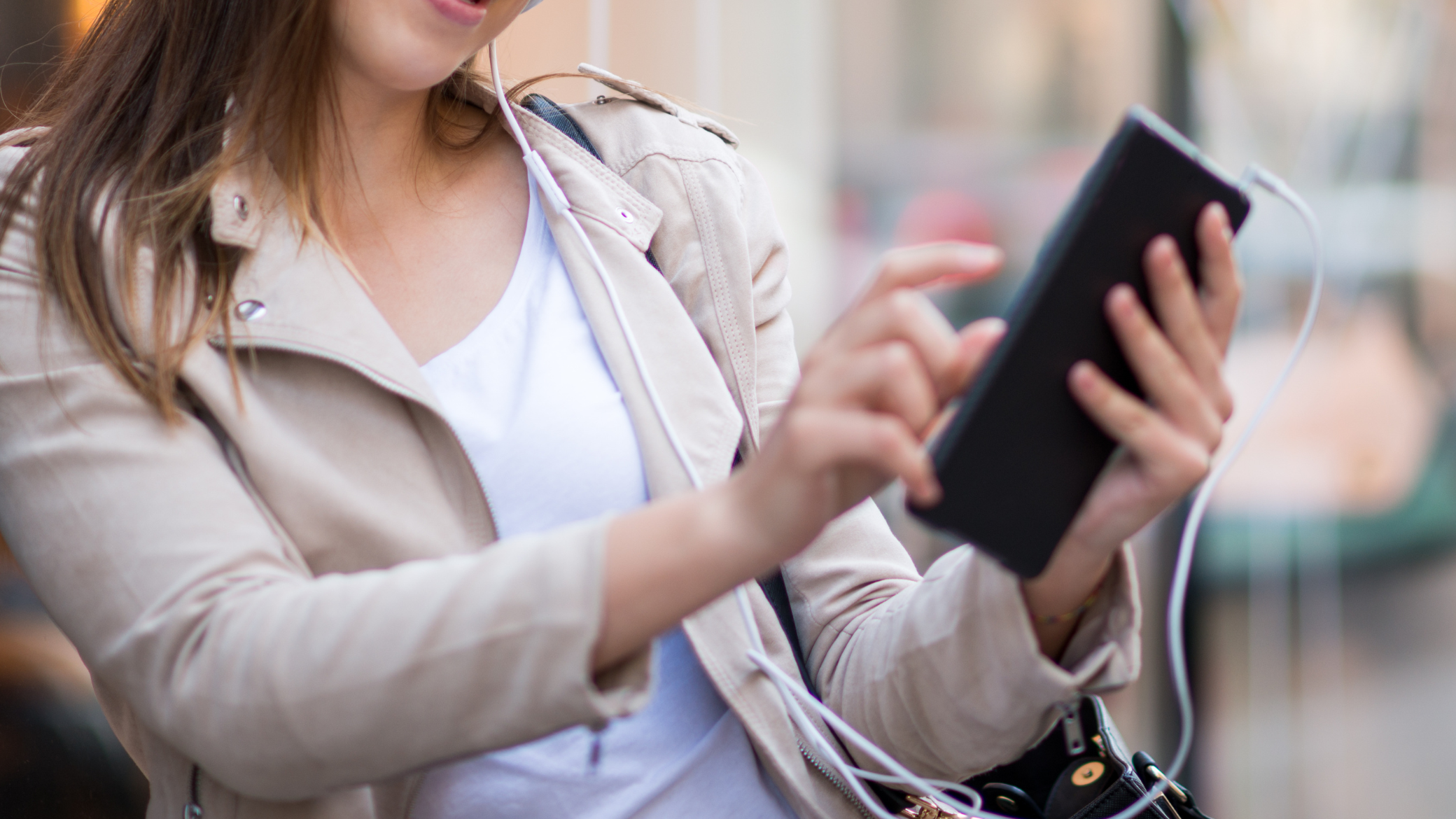 Young woman with headphones using a tablet on the street