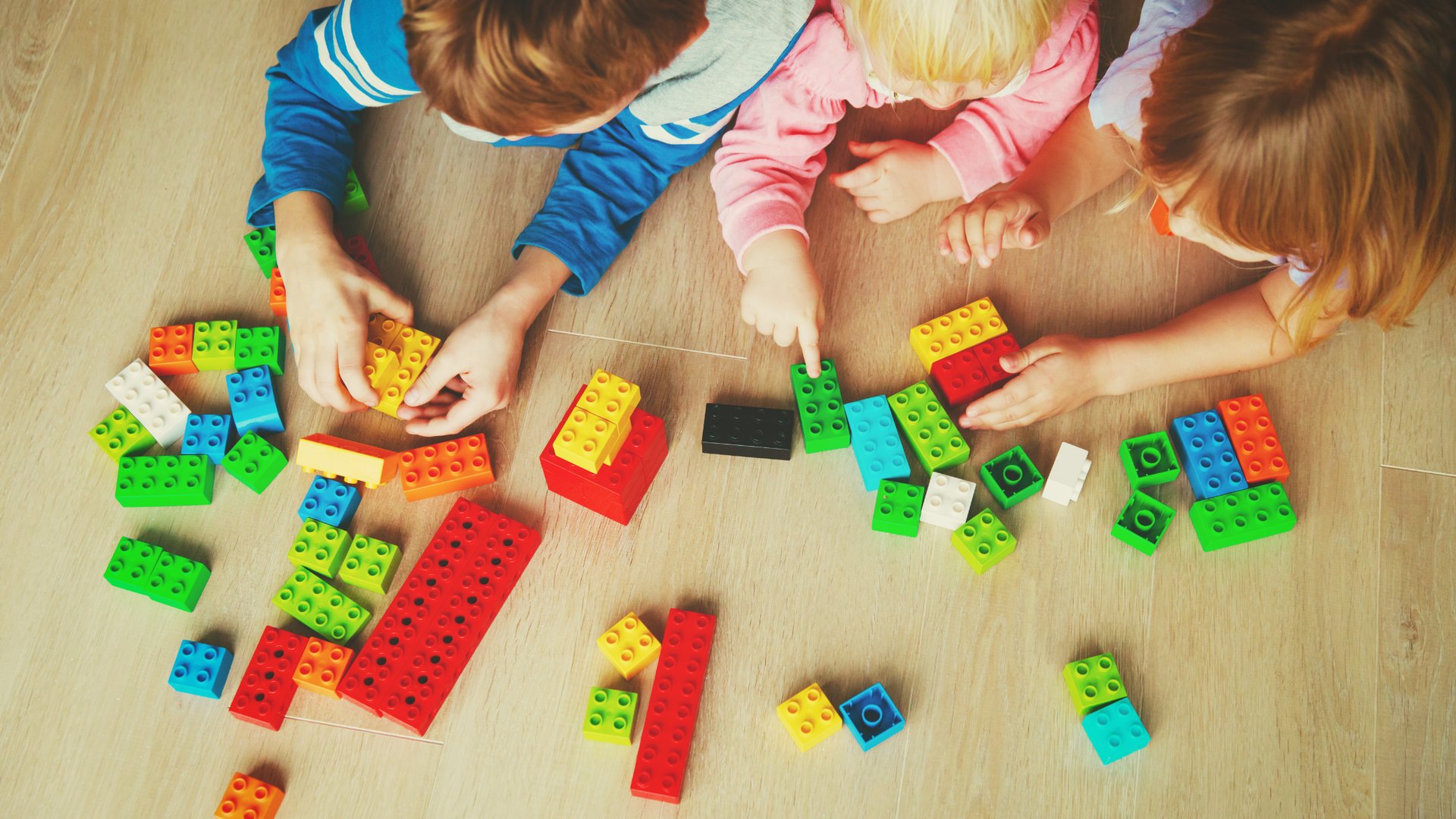 Niñas y niños jugando con bloques de construcción de colores