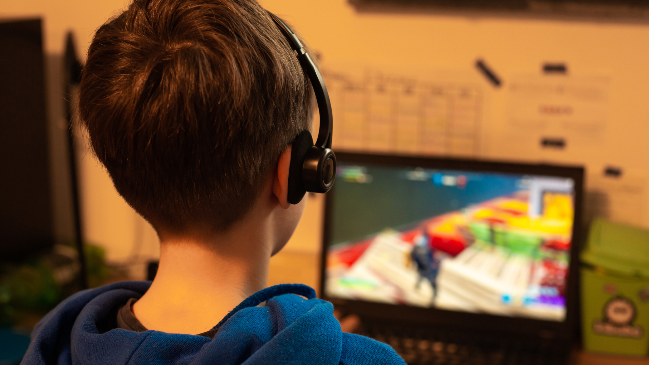 Young person playing on a computer with a headset, brand experience on Roblox by Kidscorp